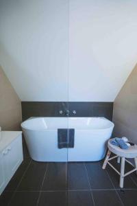 eine weiße Badewanne im Bad mit einem Hocker in der Unterkunft Hampton Bliss Kiama in Kiama Downs