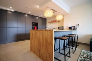 a kitchen with a bar with stools and cabinets at LUXURY 4 Bedroom 4 Ensuite Home in Penarth (Pool Table Games Room & BBQ Garden) with Sea Views in Cardiff