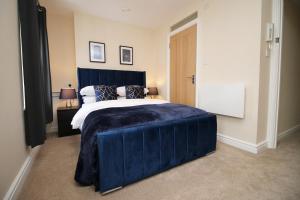 um quarto com uma cama grande e um cobertor azul em LUXURY 4 Bedroom 4 Ensuite Home in Penarth (Pool Table Games Room & BBQ Garden) with Sea Views em Cardiff
