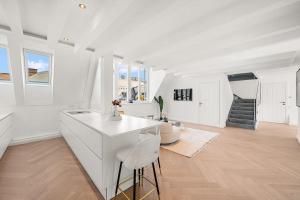 eine weiße Küche mit einer Theke und Stühlen in einem Zimmer in der Unterkunft Designer Penthouse with Balcony in Wien