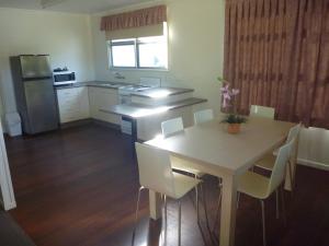 a kitchen with a table and white chairs and a refrigerator at Lake Monduran Holiday Park in Gin Gin