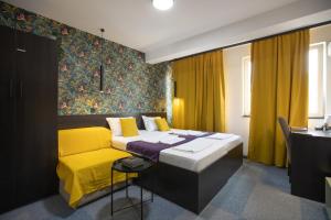 1 dormitorio con cama y sofá amarillo en 4 Rooms Apartments, en Niš