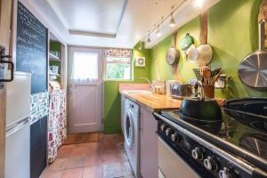 une cuisine avec des murs verts et une cuisinière four supérieur dans l'établissement Lilac Cottage, Wenhaston, à Halesworth 15 autres photos