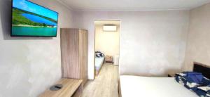 a room with a bed and a television on a wall at AGIRIJA in Panemunė