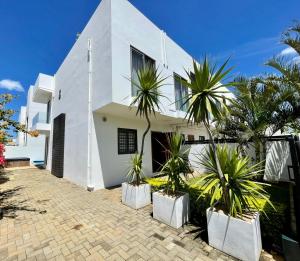 a white house with palm trees in front of it at Duplex - piscine, jacuzzi & vues in Flic-en-Flac