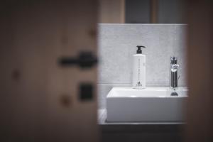 a bathroom sink with a soap dispenser on it at Kronplatz-Resort Berghotel Zirm in Valdaora +97 photos