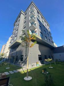 een hoog gebouw met een boom ervoor bij YOUR HOUSE Apart Otel in Karaköprü Köyü