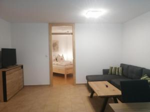 een woonkamer met een bank en een tafel en een slaapkamer bij Appartement Irmi in Söll