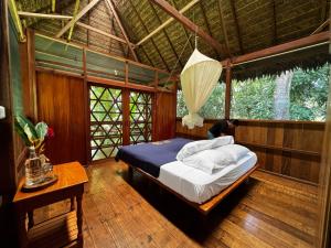 1 dormitorio con 1 cama en una habitación con ventanas en Hacienda Herrera Tambopata en Puerto Maldonado