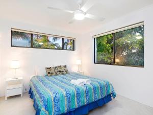 a white bedroom with a bed and two windows at Soundhaven Apartment 4, Noosa Heads in Noosa Heads