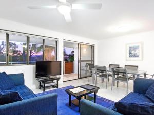 a living room with blue couches and a dining room at Soundhaven Apartment 4, Noosa Heads in Noosa Heads