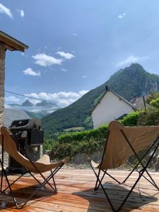 two chairs sitting on a deck with a grill at chalet en montagne in Lées-Athas