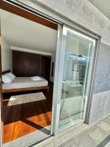 ヴィアナ・ド・カステロにあるRiver House Vianaのベッド1台とガラスのスライドドアが備わる客室です。