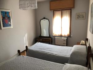 1 dormitorio con 2 camas, espejo y ventana en Casa Anna, en Crosa
