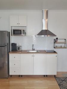 uma cozinha com armários brancos e um frigorífico de aço inoxidável em La Gentilhommière Motel et Suites B Vue sur Mer em Saint-Siméon