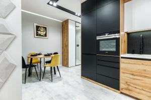 una cocina con armarios negros y una mesa con sillas en Apartament Active Residence, en Lublin