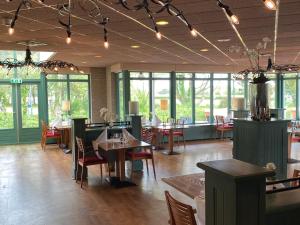 una sala da pranzo con tavoli, sedie e finestre di Amelander Kaap 109 a Hollum