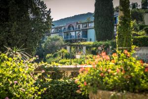 une maison au milieu d'un jardin fleuri dans l'établissement Aec Village Vacances - Les Cèdres, à Grasse