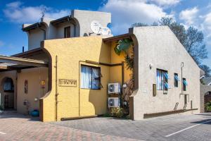 a yellow and white building with blue windows at Woodpecker's Inn Guest House in Kempton Park