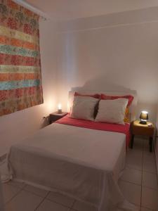um quarto com uma cama com um cobertor vermelho e uma janela em Balaou em Les Anses-dʼArlets
