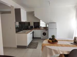 a kitchen with white appliances and a table with a bowl of fruit at Balaou in Les Anses-dʼArlets