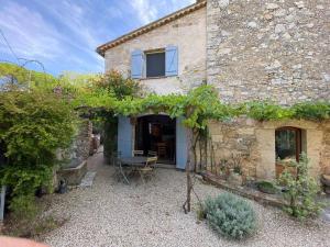 uma vista exterior para uma casa de pedra com uma mesa em 06AW - Mas en pierre provençal rénové au calme em Le Rouret