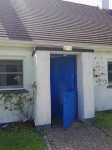 eine blaue Tür an einem Haus mit Fenster in der Unterkunft Longford Holiday Blue Sky Self Catering Cottage 