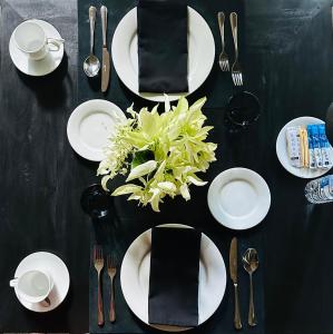 uma mesa preta com pratos e utensílios brancos em Saffron Robes Living em Hikkaduwa