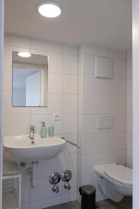 a white bathroom with a sink and a toilet at Wohnperle im pulsierenden Dornbirn - Ibiza 3 in Dornbirn