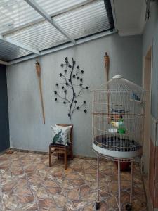 une cage pour oiseaux dans une pièce avec un arbre sur le mur dans l'établissement Dormitório 2 aconchegante a 2km de Alphaville, à Barueri