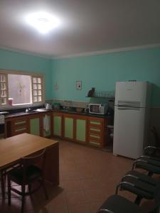 Il comprend une cuisine équipée d'une table et d'un réfrigérateur blanc. dans l'établissement Dormitório 2 aconchegante a 2km de Alphaville, à Barueri