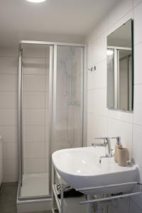 a white bathroom with a sink and a shower at Boho-Wohnflair mitten in Dornbirn - Bali 2 in Dornbirn +4 photos