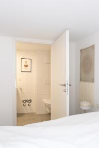 a white bathroom with a toilet and a shower at Boho-Wohnflair mitten in Dornbirn - Bali 2 in Dornbirn