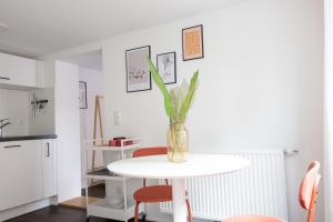a white table with a vase with a plant on it at Boho-Wohnflair mitten in Dornbirn - Bali 2 in Dornbirn