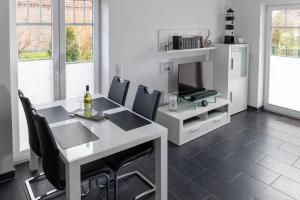 een eetkamer met een witte tafel en stoelen en een televisie bij Ferienhaus Wattwurm Neu in Hooksiel