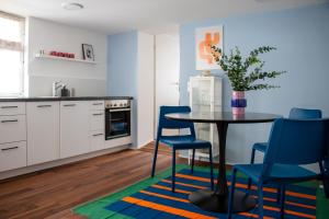 a kitchen with a table and two blue chairs and a table at Gemütliches City Apartment im Zentrum von Dornbirn, Barcelona 4 in Dornbirn