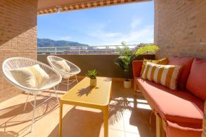 a balcony with chairs and a couch and a table at Beach Paradise Flat in Denia Centre w/ Large Pool in Denia