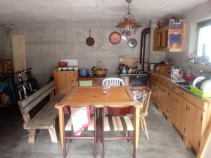 uma cozinha com uma mesa de madeira e cadeiras em Ostello Casa Morit em Pontebba