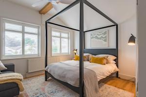 ein Schlafzimmer mit einem schwarzen Himmelbett und gelben Kissen in der Unterkunft Little Beach House by Bloom Stays in Whitstable