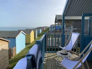 eine Terrasse mit 2 Stühlen und farbenfrohe Strandhütten in der Unterkunft Little Beach House by Bloom Stays in Whitstable