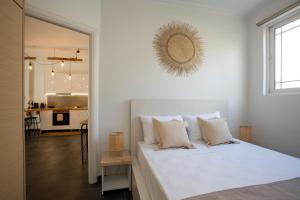 a white bedroom with a large white bed with a mirror at Silk Mill Metaxourgeio, Athens Centre in Athens