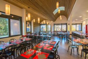 a dining room with tables and chairs and windows at AEC Vacances - Les Becchi in Samoëns