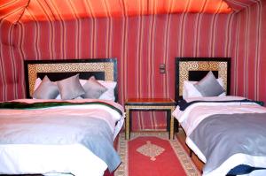 two beds in a room with red walls at BIVOUAC SINAS in Rissani