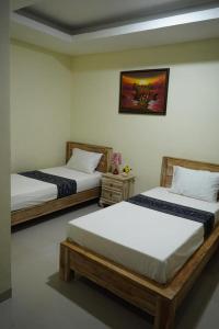 Pokój z dwoma łóżkami i zdjęciem na ścianie w obiekcie Umah Desa w mieście Banjarangkan