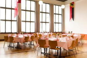 Habitación grande con mesas, sillas y manteles rosados. en Gasthof zum Wilden Mann, en Aarwangen