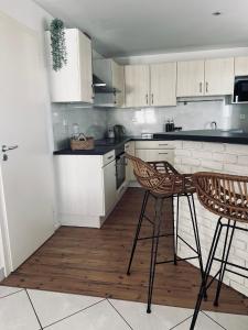 una cocina con armarios blancos y 2 sillas. en Richard's appartement 6 personnes 3 chambres, en Pulversheim