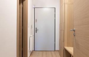 Una puerta blanca en una habitación con suelo de madera en Panoráma Sétány Apartman Fonyód, en Fonyód