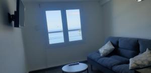 uma sala de estar com um sofá azul e uma janela em Au Panorama F3 2 chbres em La Possession