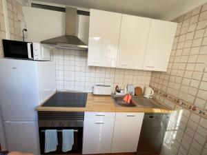 cocina con armarios blancos, fregadero y nevera en Trinimat Ferienwohnung Teneriffa Nord 2 en Santa Úrsula