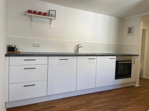a kitchen with white cabinets and a sink at Modernes Stadtleben im gemütlichen City Apartment Dornbirn, London 8 in Dornbirn